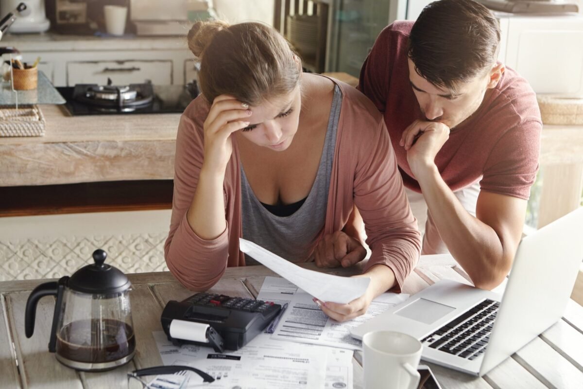 Casal preocupado analisando contas e despesas para organizar as finanças e sair das dívidas.