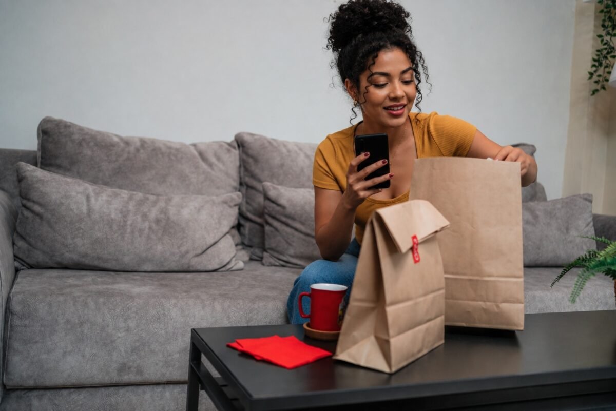 Pessoa fazendo pedido de delivery pelo celular, representando o impacto dos pequenos gastos recorrentes no orçamento.